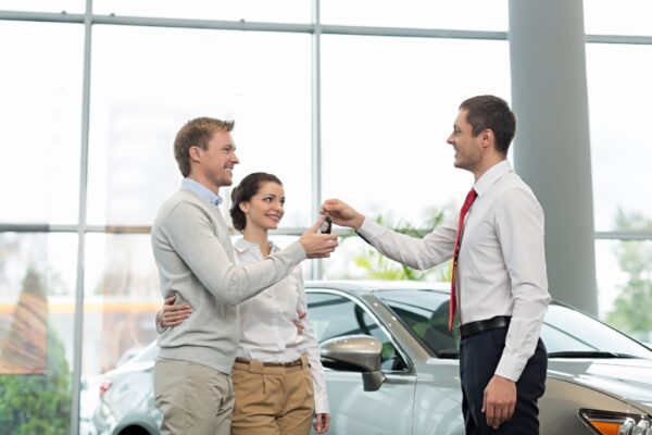 car salesman handing keys to a couple